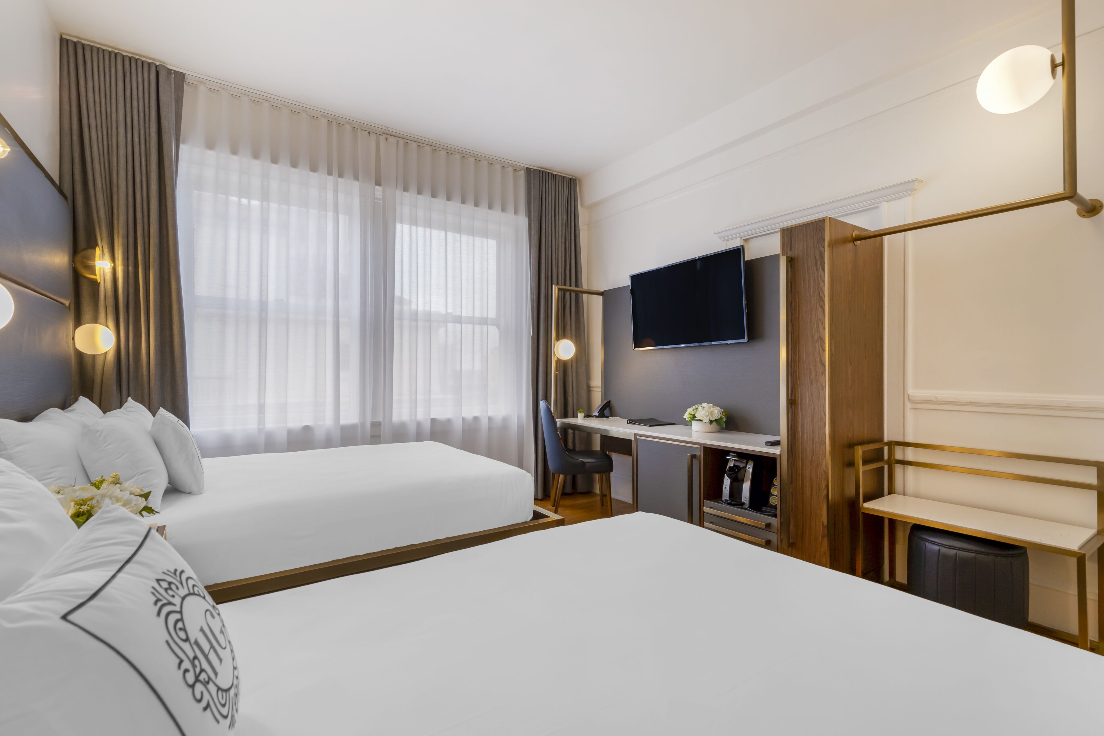 Une chambre d’hôtel avec deux lits, un bureau, une télévision et une salle de bain.