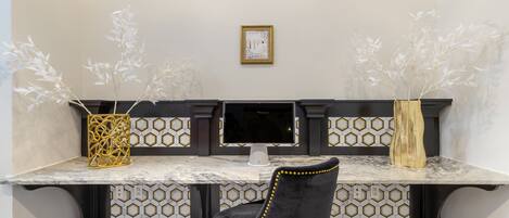 A modern kitchen with a marble countertop, a black chair, and decorative vases.