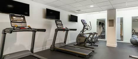 A gym with treadmills, exercise bikes, and a large mirror.