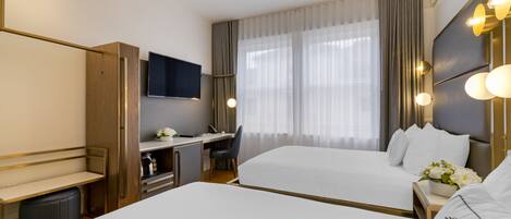 A hotel room with two beds, a desk, a chair, a TV, and a window with curtains.