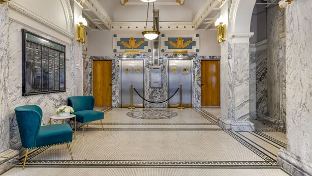 A lobby with marble floors, teal chairs, and a central elevator. - Hotel Gibbs Downtown Riverwalk (San Antonio)