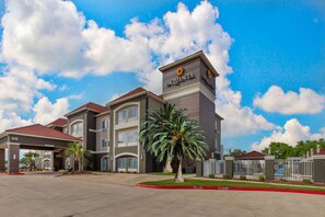 A hotel with a prominent 'La Quinta' sign, a covered parking area, and a well-maintained lawn with palm trees. - La Quinta Inn & Suites by Wyndham Port Lavaca (Port Lavaca)