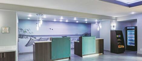 A reception area with a counter, a wall mural, and a vending machine.