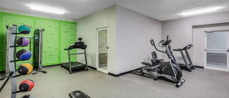 A gym with exercise equipment, a bench, and a wall with motivational text.