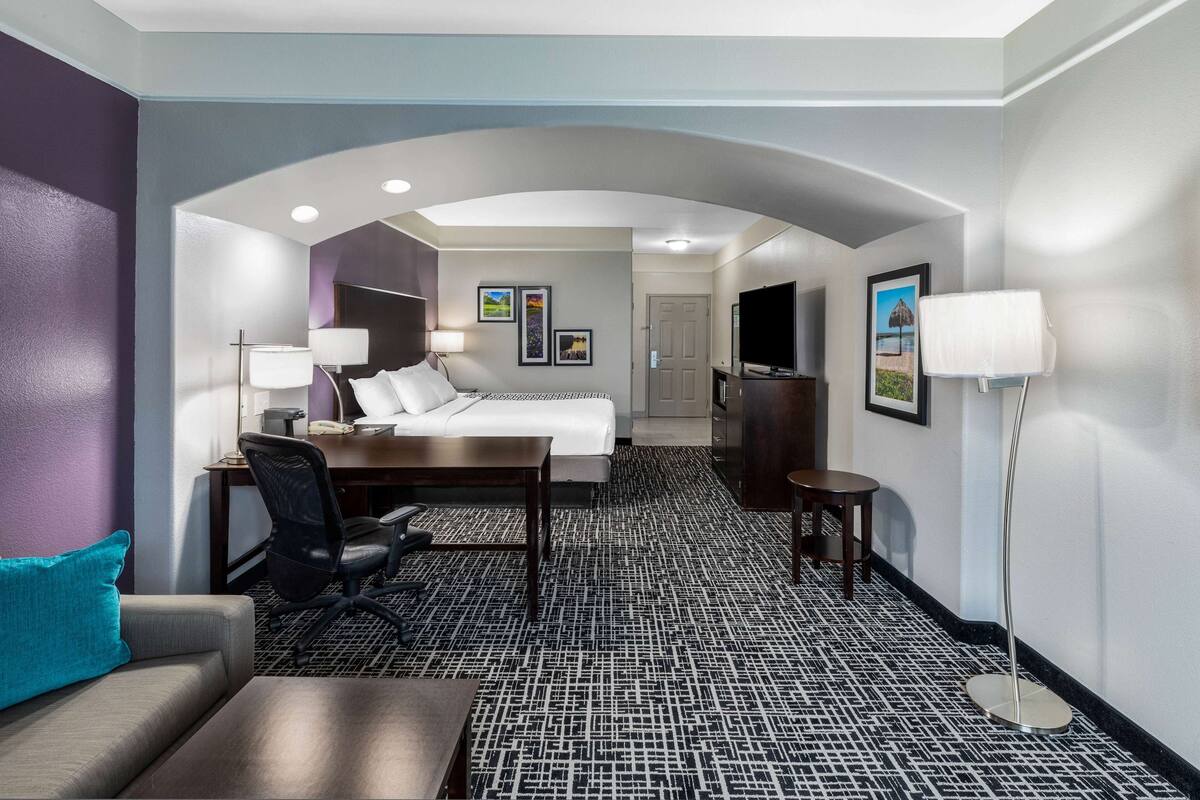 Habitación de hotel con cama, escritorio, silla y televisor.
