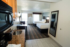 Habitación de hotel con kitchenette, dos camas, un espejo grande y vistas al exterior.