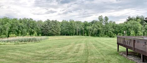 A well-maintained grassy area with a wooden deck and a pond.
