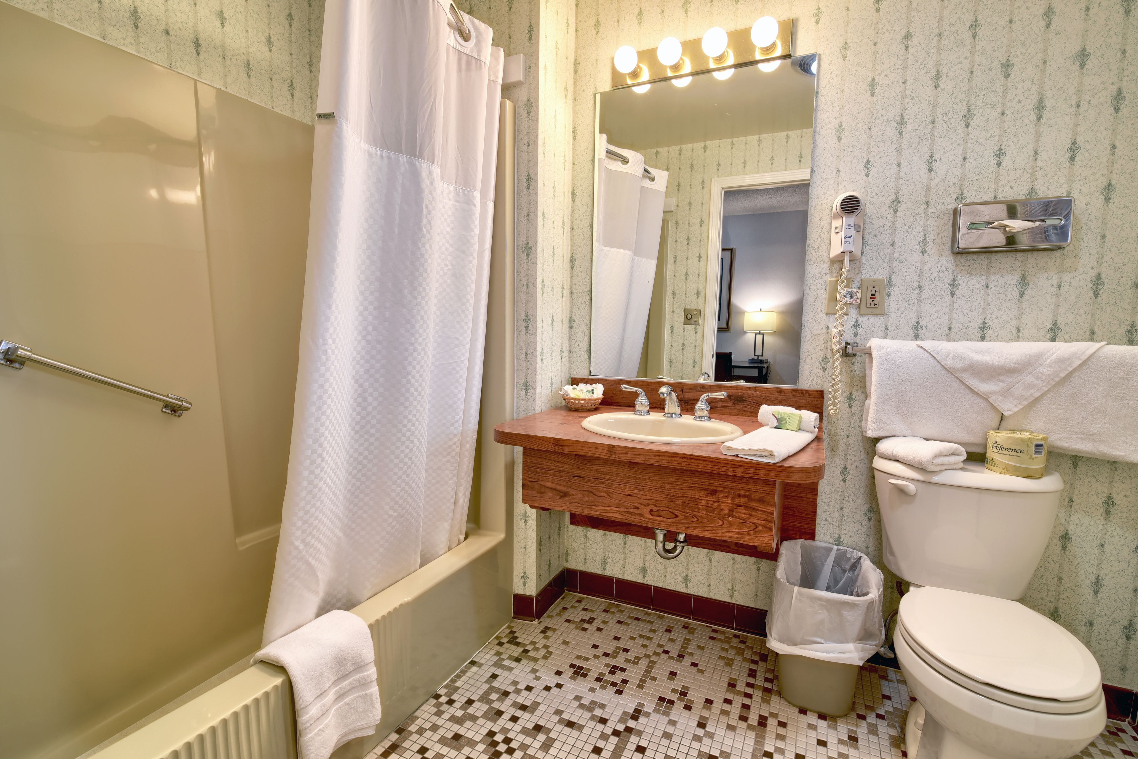 Une salle de bain équipée d’une douche, d’un lavabo, de toilettes et d’un miroir avec des lumières au-dessus.