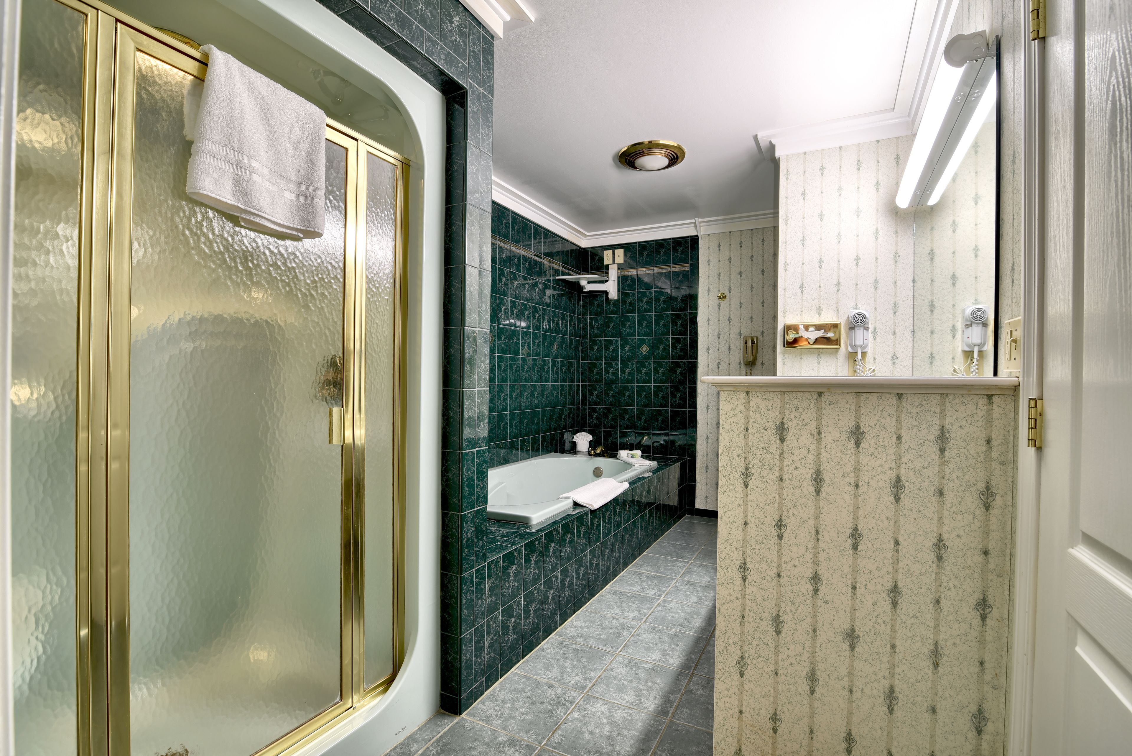 A bathroom with a glass-enclosed shower, a freestanding bathtub, and a vanity with a mirror.