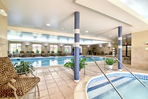 Una piscina interior con paredes de azulejos, sillas de descanso y plantas en macetas.