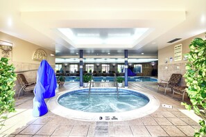 Un área de hidromasaje con suelo de baldosas, sillones de descanso y una piscina al fondo.