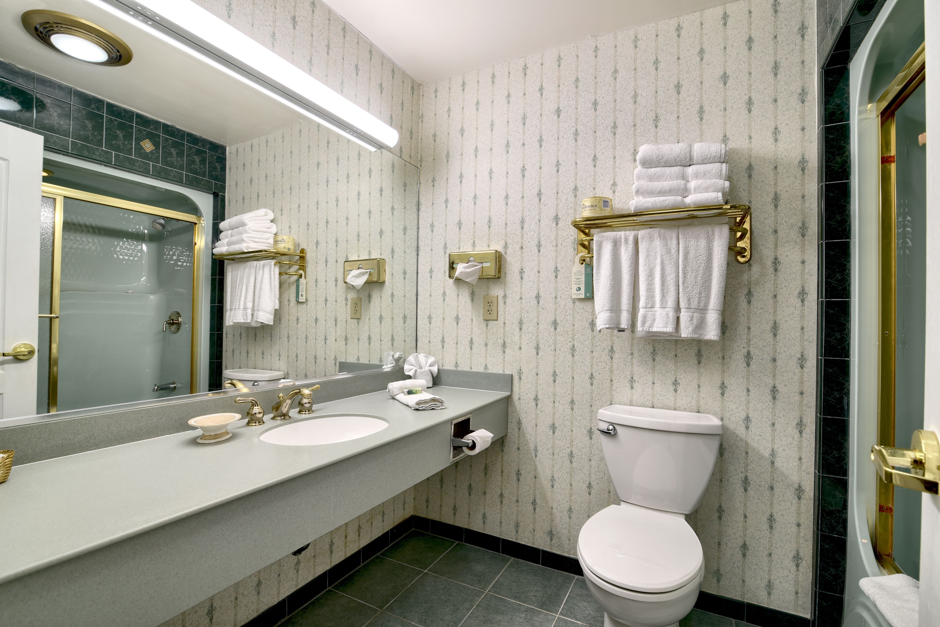 Ein Badezimmer mit einem großen Spiegel, zwei Waschbecken, einer Toilette und einem Duschbereich.
