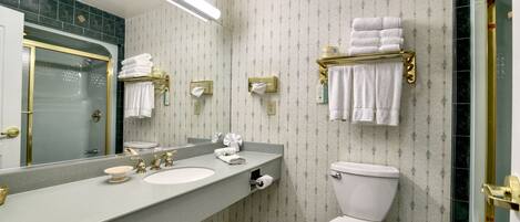 A bathroom with a large mirror, two sinks, a toilet, and a shower area.