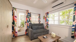 Una sala de estar con un sofá gris, una mesa de centro de madera y cortinas coloridas.