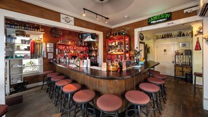 Zona de bar con taburetes de madera, estantes con botellas de licores y un letrero de neón para Jameson Irish Whiskey.