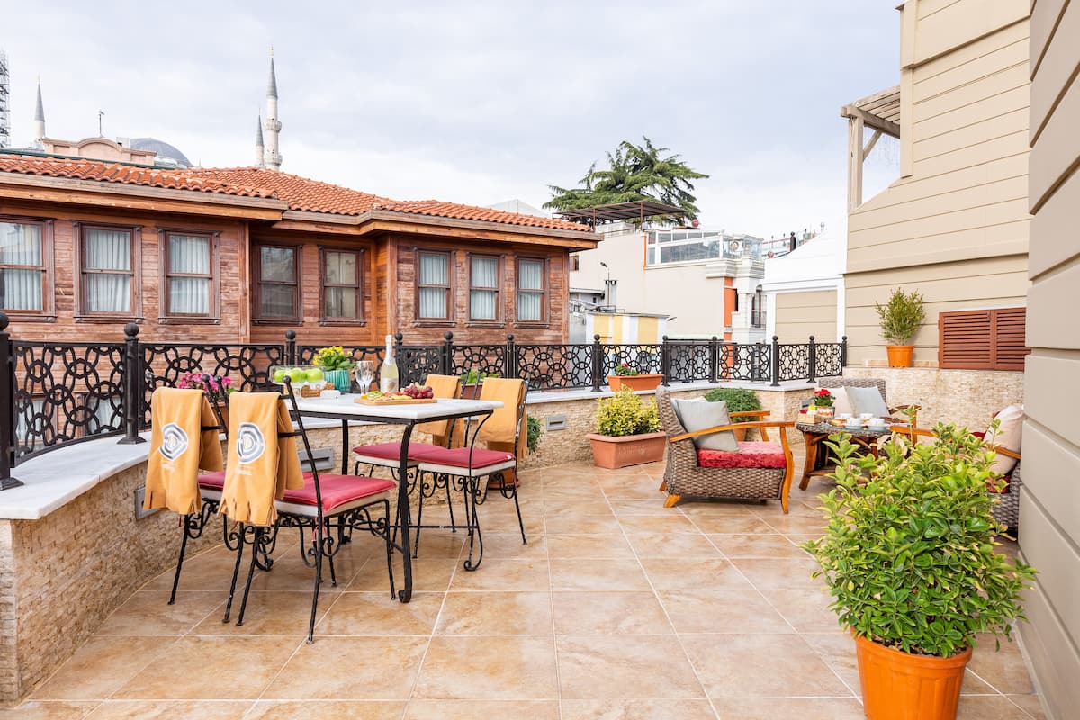 A patio area with outdoor seating, a table, and potted plants.