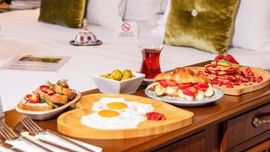 A breakfast setup on a wooden table with plates of food, including eggs, pancakes, and a bowl of fruit. - Best Point Hotel (Istanbul)