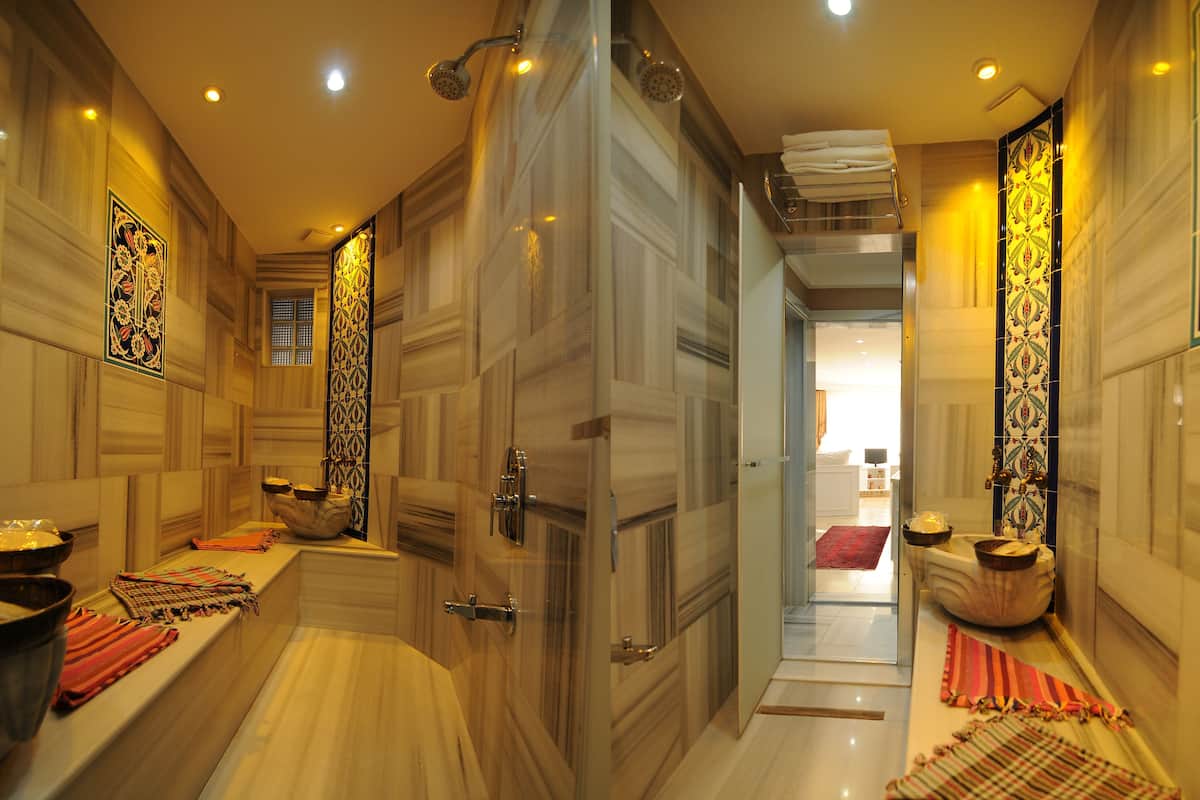 A luxurious bathroom with a marble floor, a large bathtub, and a shower area.