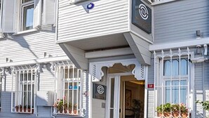 A two-story building with a balcony, a door with a sign, and a window with shutters. - Best Point Hotel (Istanbul)