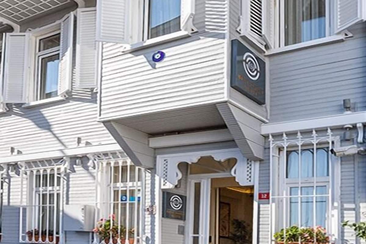 A two-story building with a balcony, a door with a sign, and a window with shutters.