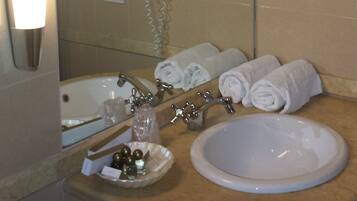 Une salle de bain équipée d’un lavabo, d’un miroir, d’un porte-serviettes et d’un sèche-cheveux fixé au mur.