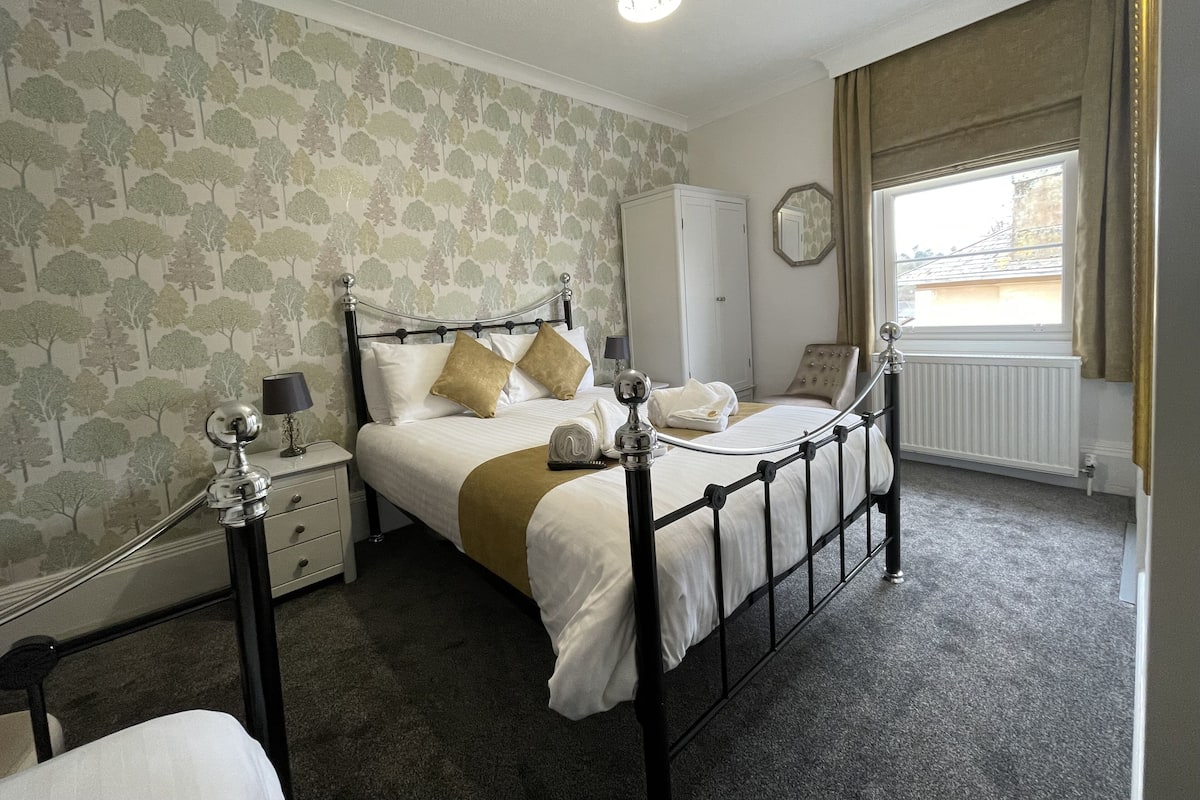 A neatly arranged bedroom with a bed, bedside tables, a wardrobe, and a window with curtains.