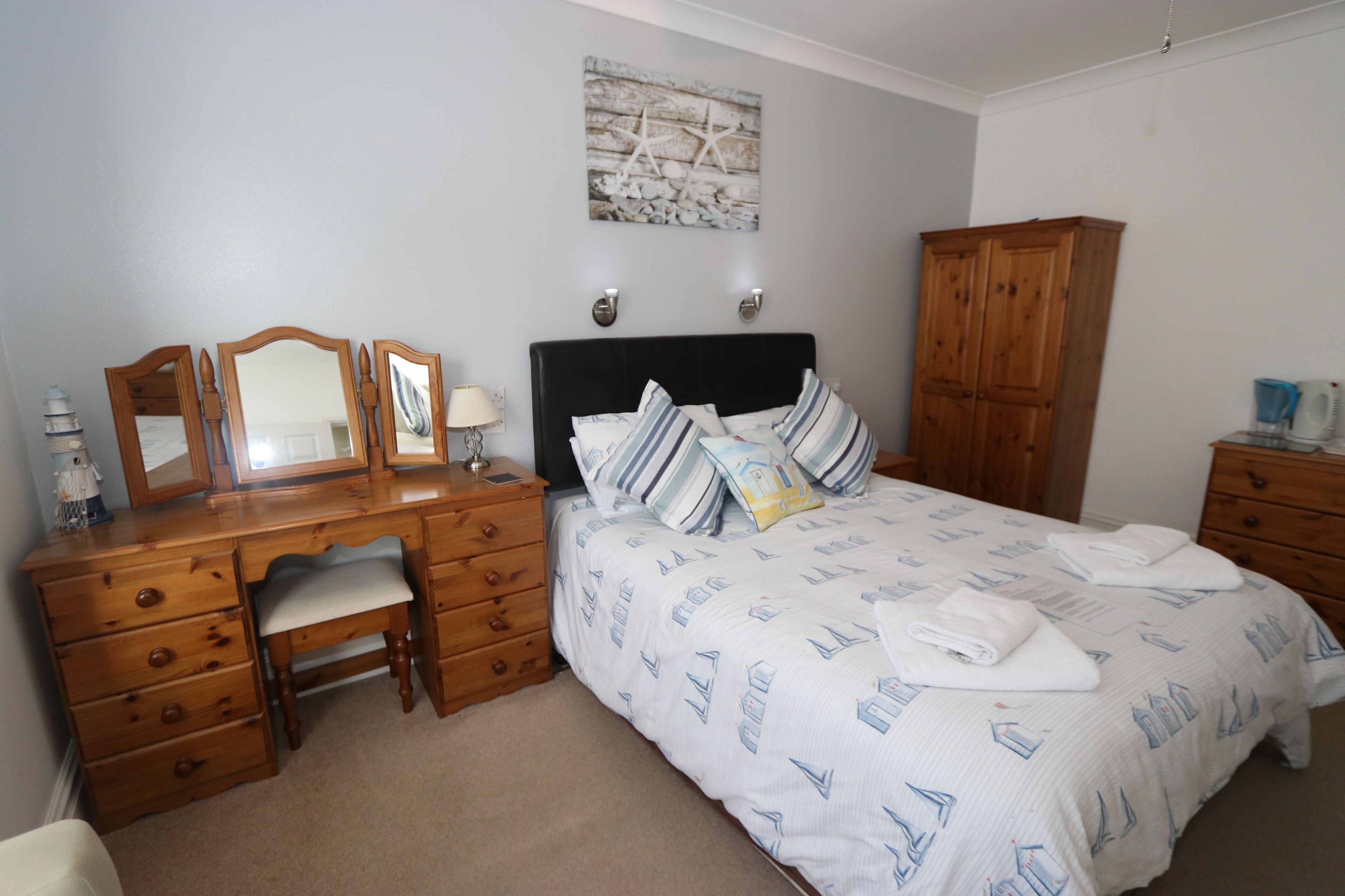 A bedroom with a bed, wooden dresser, desk, and chair.
