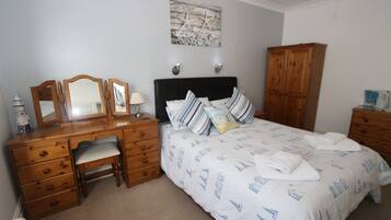 A bedroom with a bed, wooden dresser, desk, and chair.