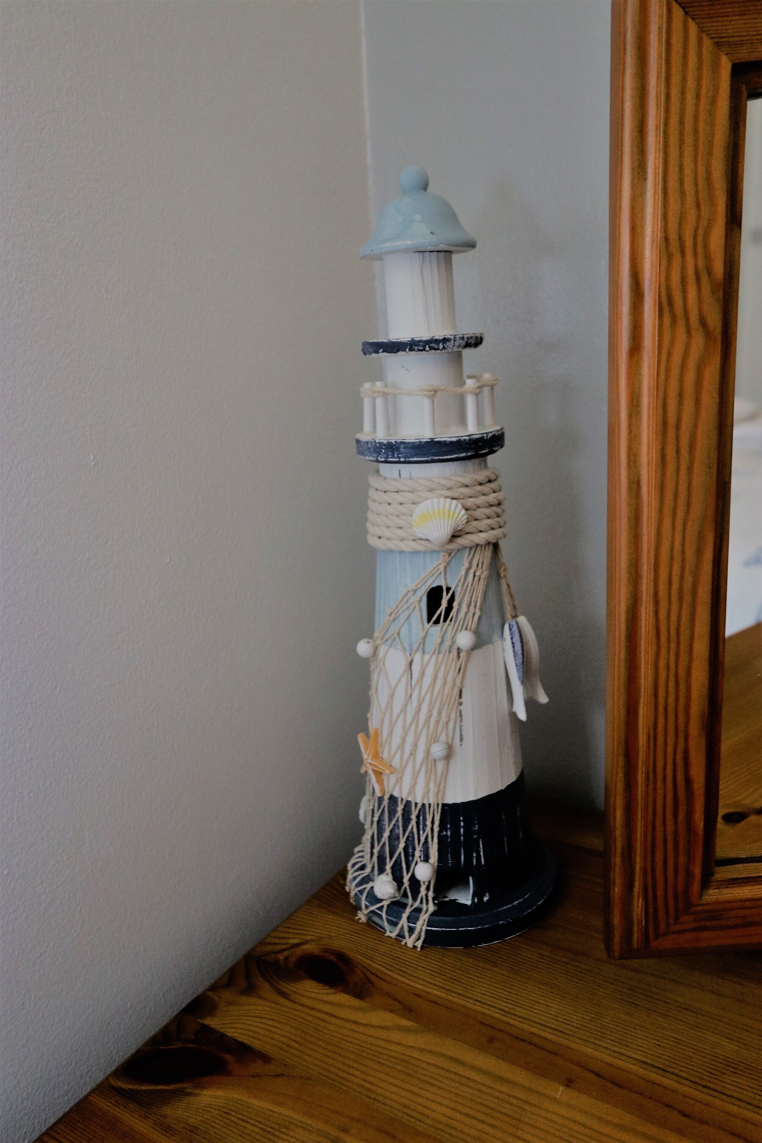 A decorative lighthouse ornament on a wooden surface.