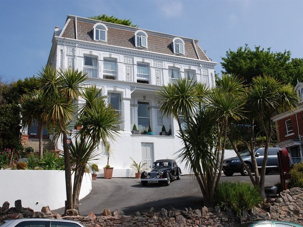 A large white building with a classic architectural style, featuring multiple windows and a central entrance.
