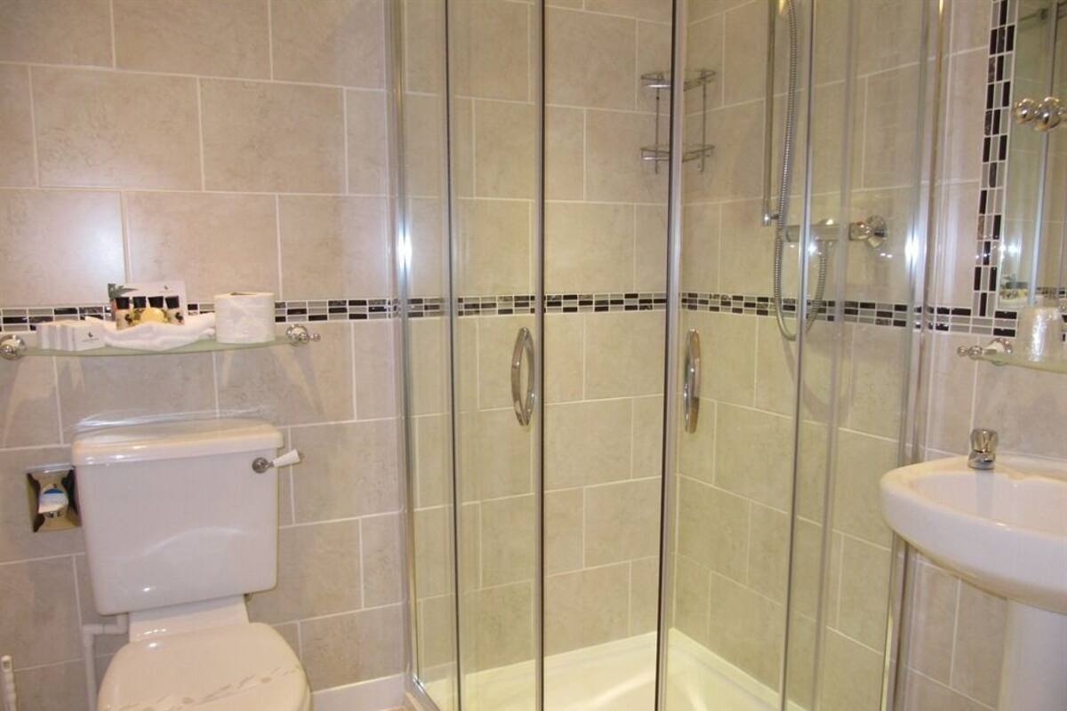A bathroom with a glass-enclosed shower, a toilet, and a sink.