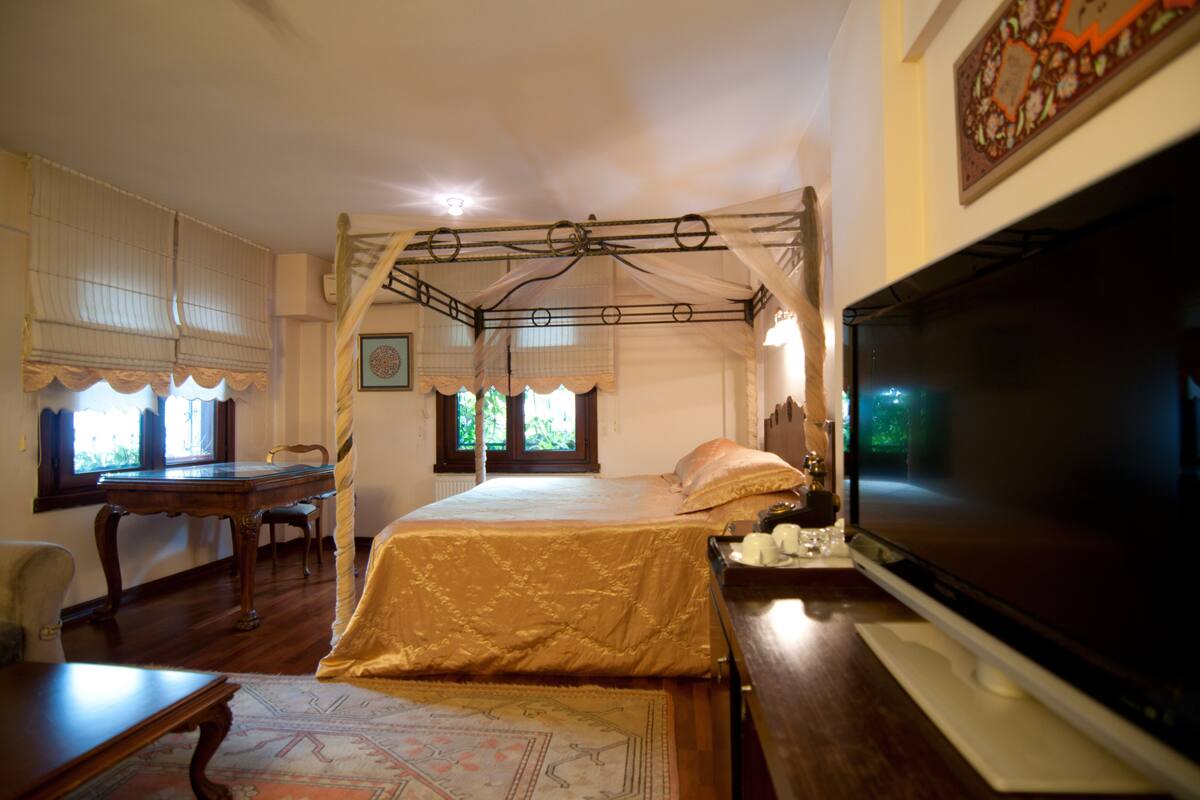 A bedroom with a bed, a TV, a desk, and a chair.