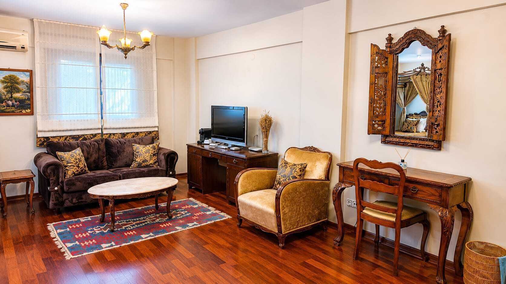 A living room with a sofa, armchair, coffee table, TV, and a decorative mirror.