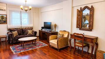 A living room with a sofa, armchair, coffee table, TV, and a decorative mirror.