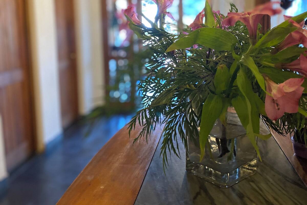 Un pasillo con puertas de madera y una mesa de mármol con un florero.