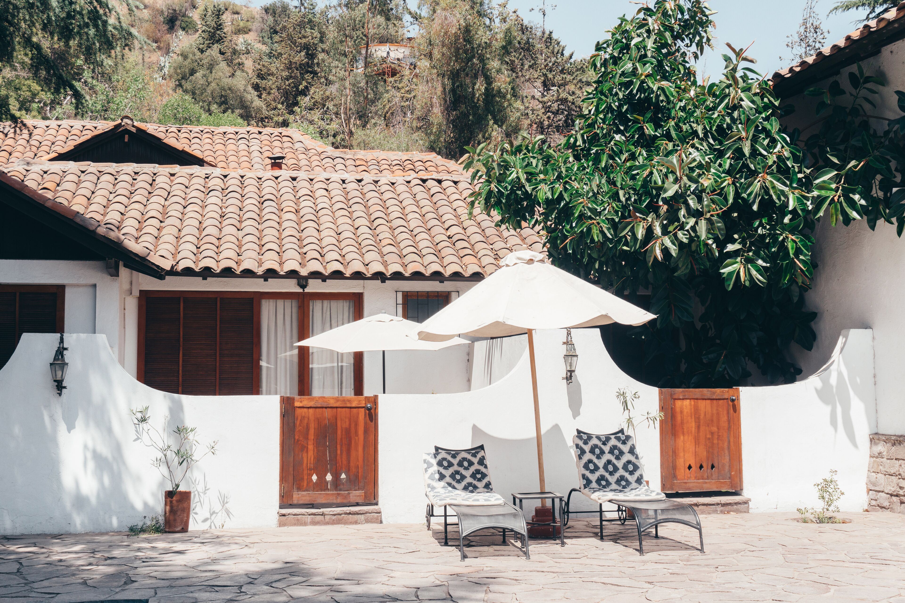 A patio with outdoor furniture, a white wall, and a tiled roof.