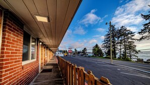 A brick building with a covered walkway and a view of the road and trees.