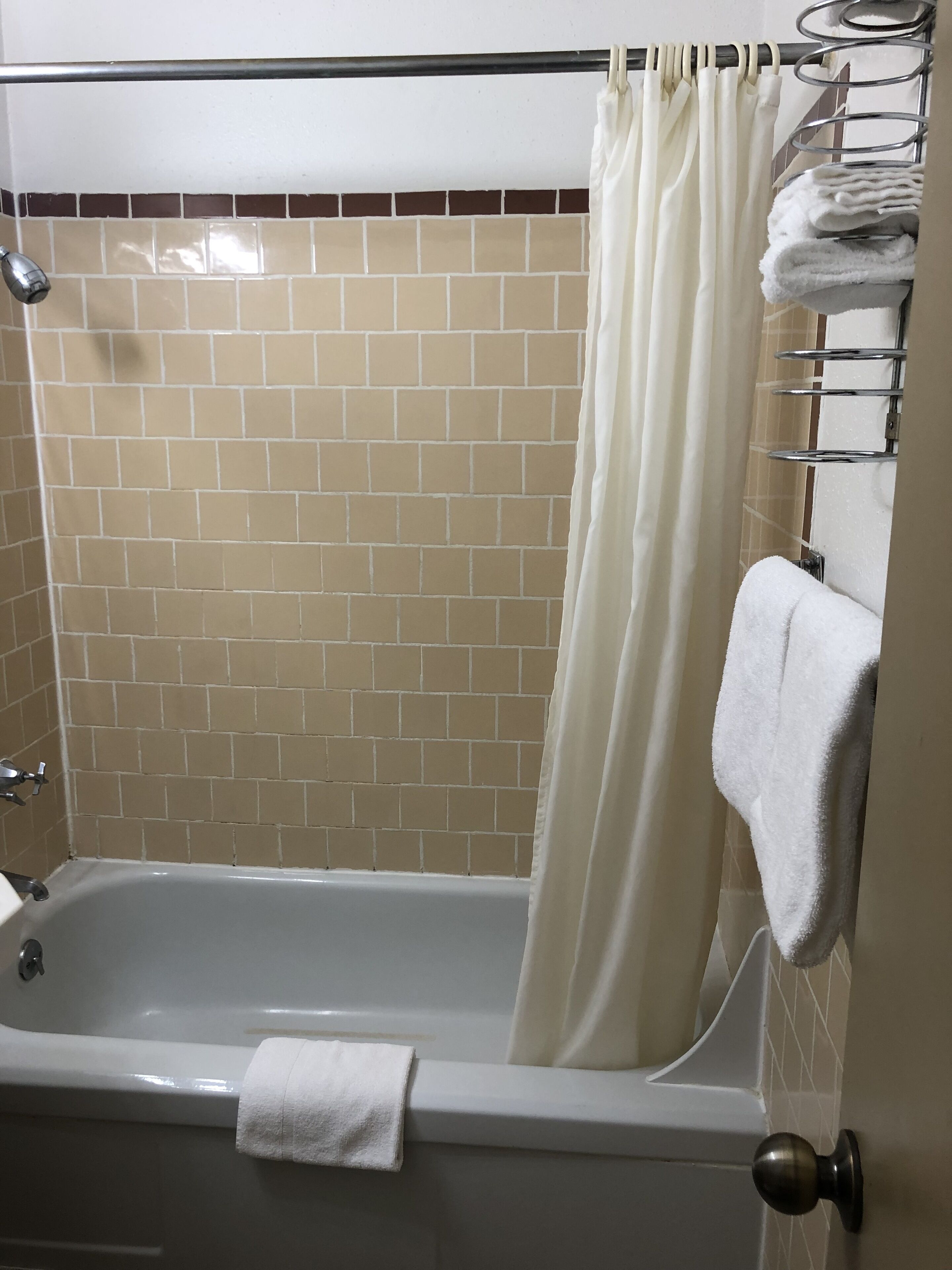Ein Badezimmer mit einer Badewanne, einer Duschvorhang und einem Handtuchhalter mit Handtüchern.