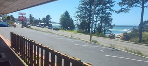 Una carretera costera con un letrero del Four Winds Inn, vista al océano y una cerca de madera a un lado del camino.