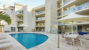 A modern building with a swimming pool, outdoor seating, and multiple balconies. - Seashells Scarborough (Scarborough)