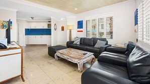 A living room with a black leather sofa, a coffee table, and a kitchen in the background. - Seashells Scarborough (Scarborough)