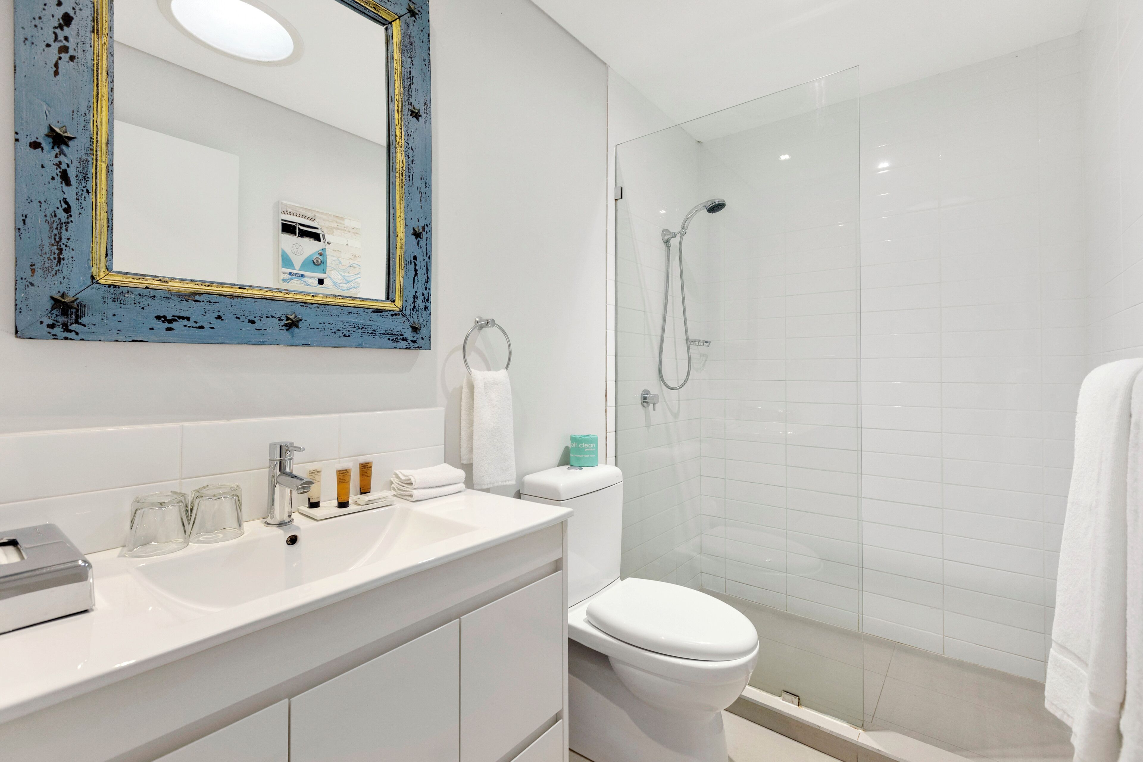 A modern bathroom with a white sink, a glass shower enclosure, and a toilet.
