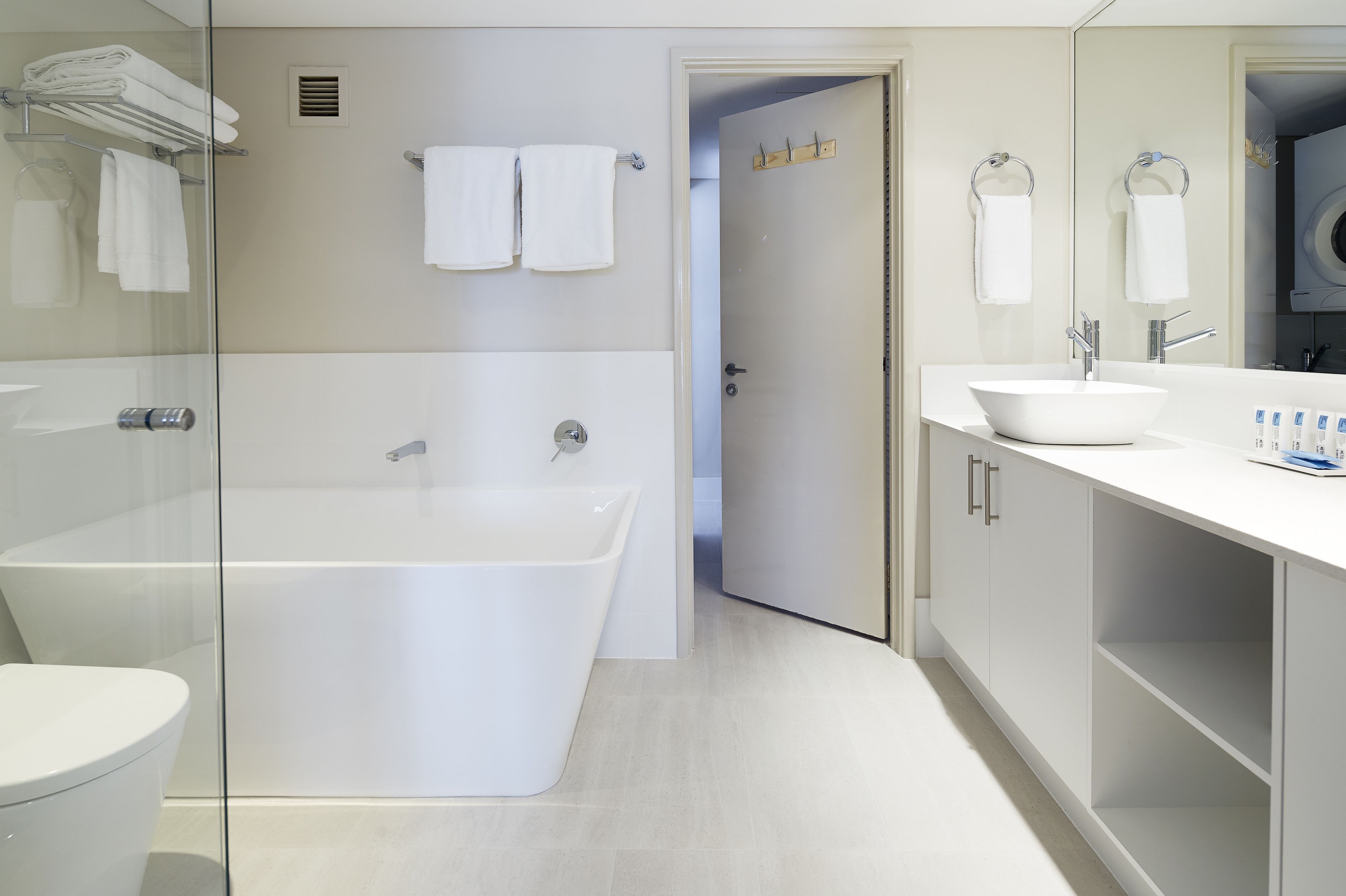 A modern bathroom with a glass-enclosed shower, a freestanding bathtub, and a white vanity with a sink and mirror.