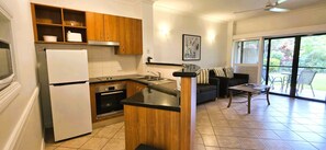 Cocina compacta con refrigerador, horno y armarios de madera.