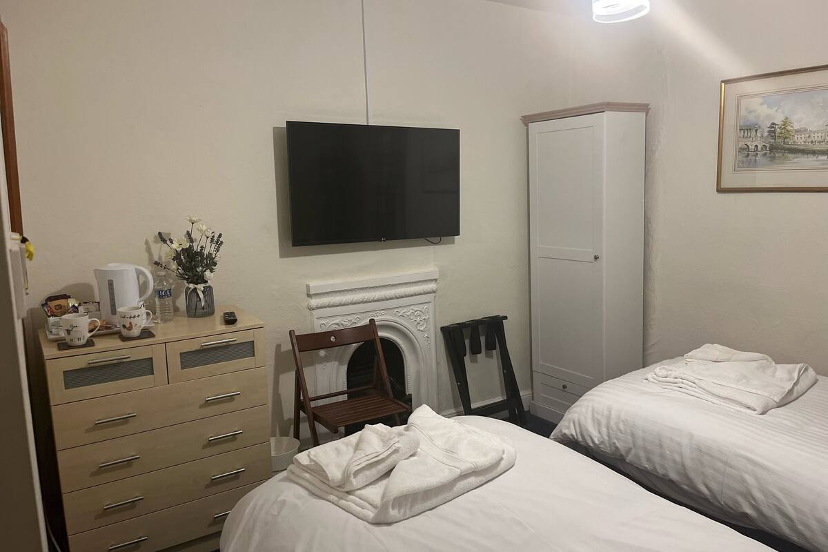 A hotel room with a bed, a dresser, a television, a fireplace, and a wardrobe.