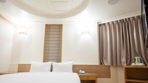 Une chambre d’hôtel comprenant un lit, une table de chevet et un petit bureau avec un téléphone.