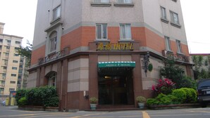Un hôtel situé à l’angle d’une rue, avec plusieurs étages et une enseigne indiquant qu’il s’agit d’un hôtel.