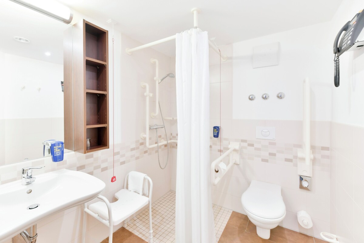 A modern bathroom with a shower, toilet, and sink.