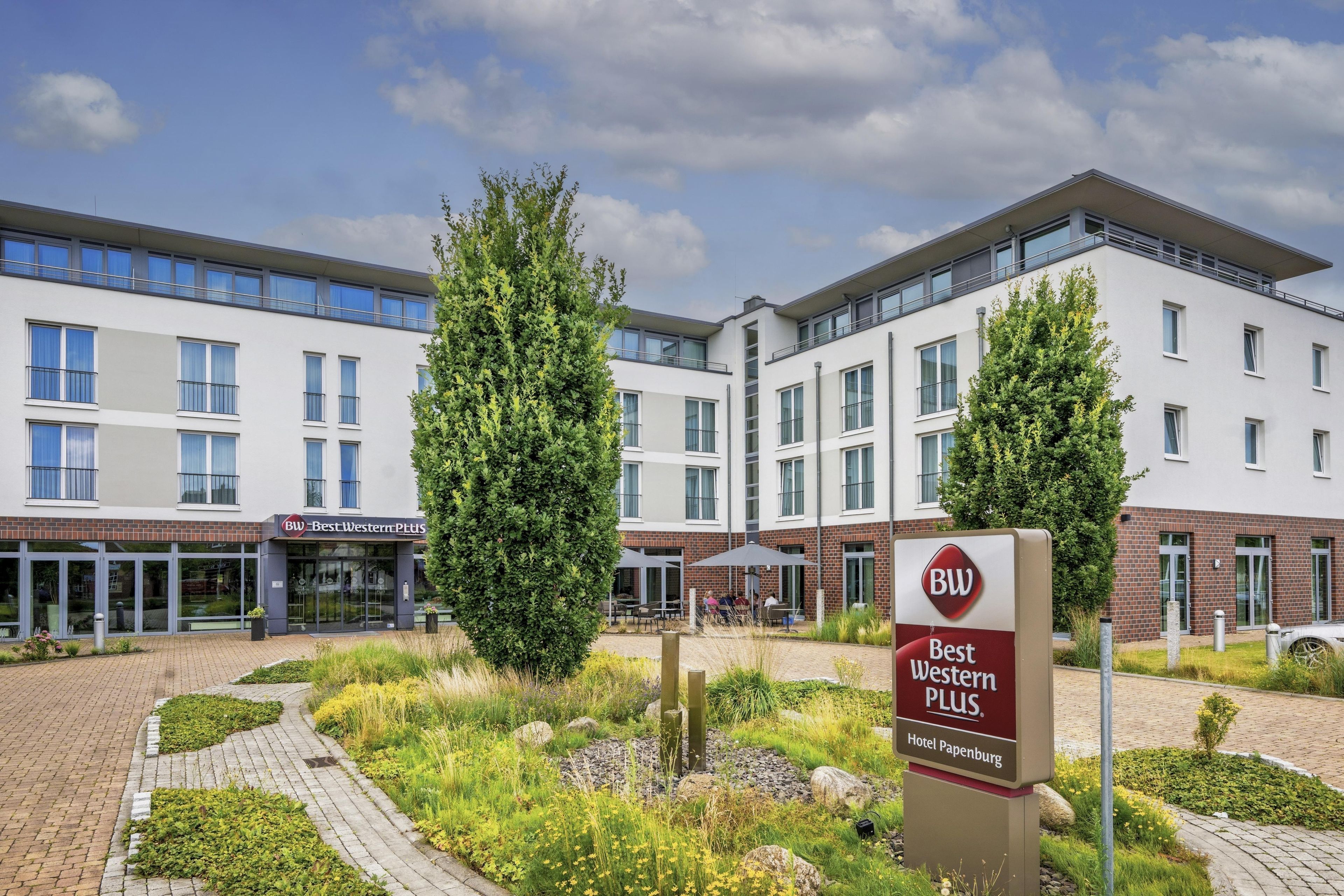 Ein Hotel mit modernem Design, das einen zentralen Innenhof mit Grünflächen und Sitzbereichen bietet.