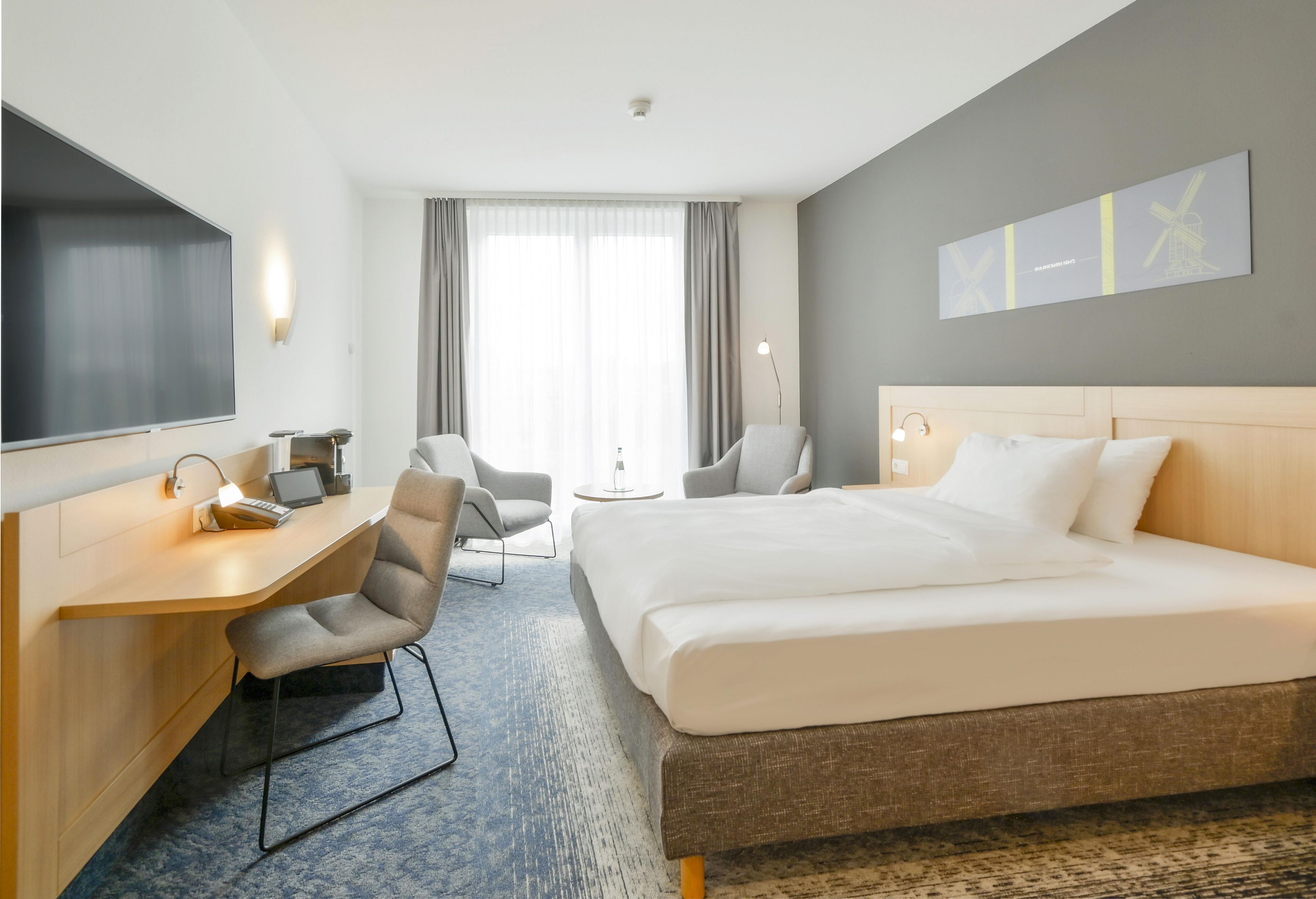 Une chambre d’hôtel équipée d’un lit, d’un bureau, d’une chaise et d’un téléviseur.